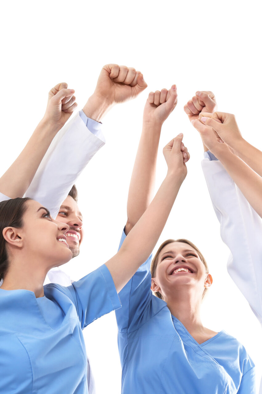 Team of medical doctors raising hands together on white background. Unity concept